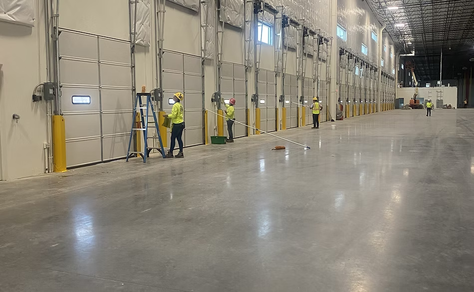 Crew cleaning overhead doors and floors in a large warehouse bay