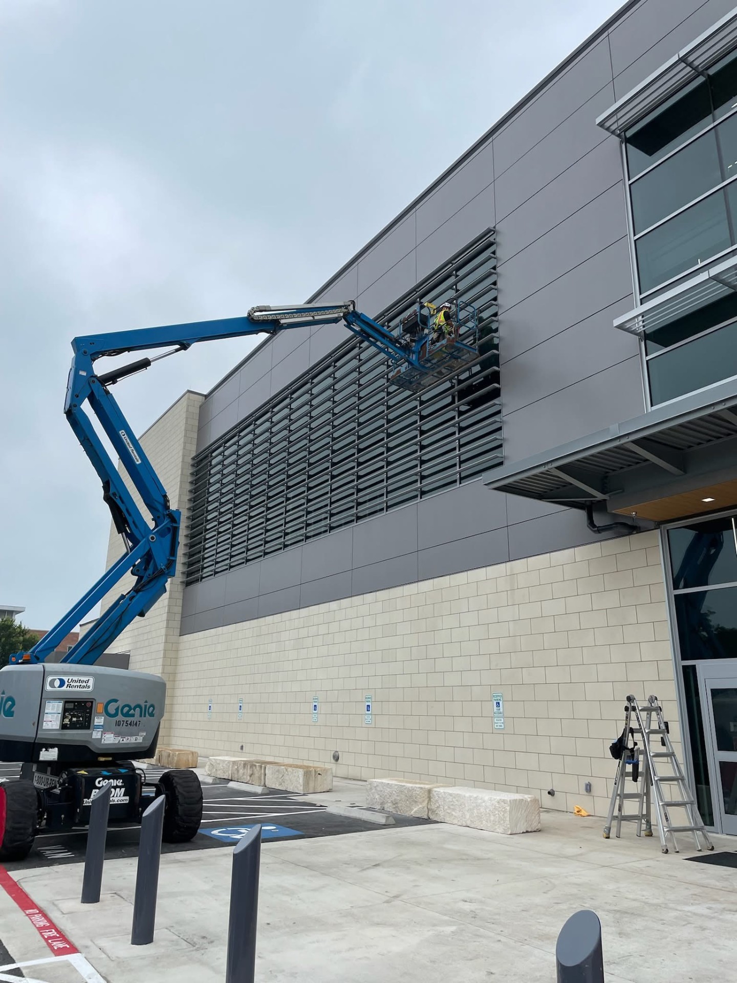 Boom lift raising a technician to clean exterior louvers on a commercial building