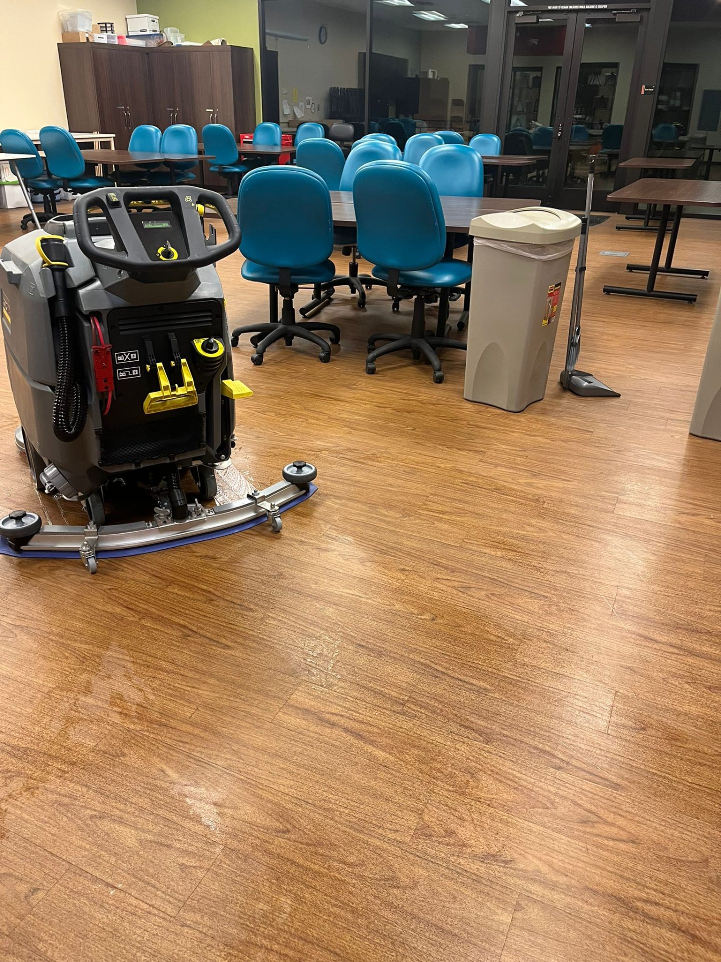JANI-WORKS technician running an auto-scrubber through a staff break room